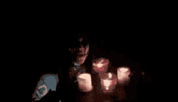 a man sitting in the dark with candles around him