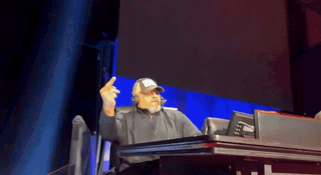 a man wearing headphones and a hat with the word texas on it gives the middle finger