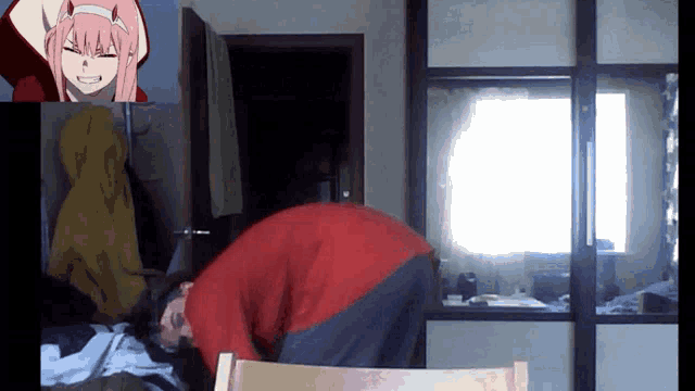 a man in a red sweater is kneeling down in front of a picture of a girl with pink hair