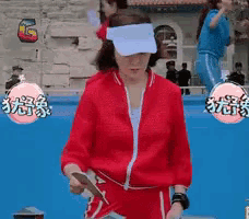 a woman wearing a red jacket and white visor stands in front of a pool