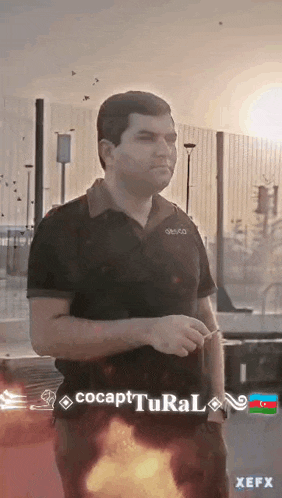 a man in a black shirt is standing in front of a fence with a fire coming out of his pants .