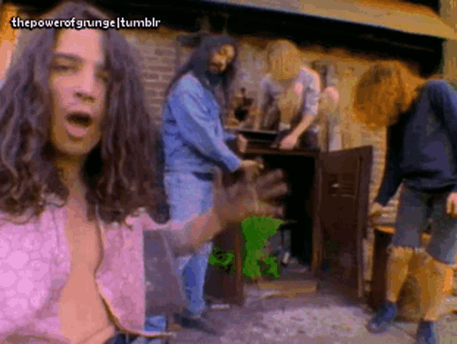a group of men with long hair are standing outside a building .