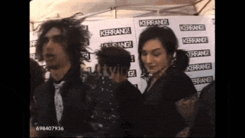 a group of people are standing in front of a wall that says kerrang