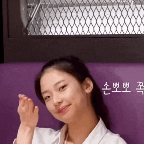 a young woman in a white robe is sitting on a purple couch and smiling .