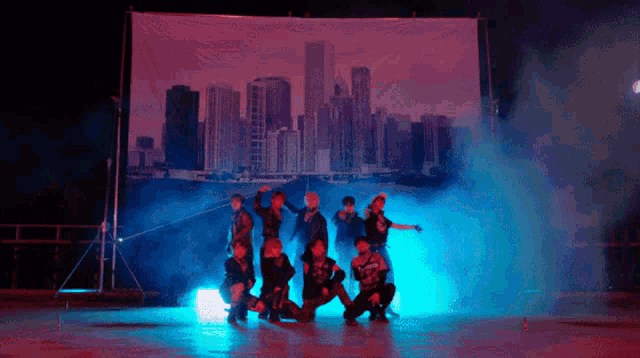 a group of people are dancing in front of a large screen with a city skyline in the background