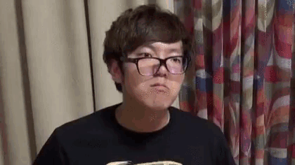 a man wearing glasses and a black shirt is standing in front of a curtain and making a funny face .