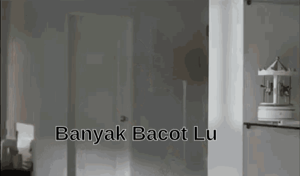 a man is standing in a room with the words banyak bacot lu written above him