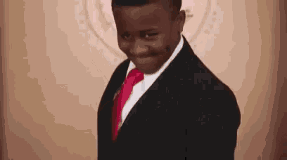 a young boy wearing a suit and tie is smiling .