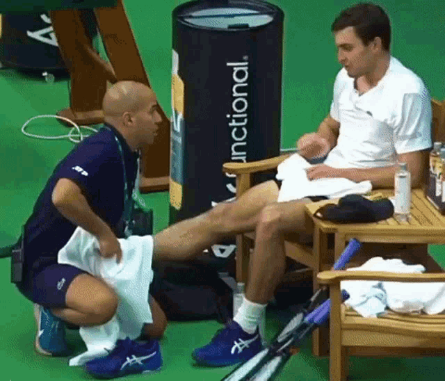 a man in a white shirt is sitting in a chair talking to a man in a blue shirt with functional written on it