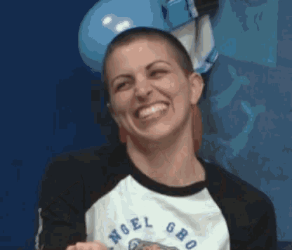 a woman with a shaved head wearing a shirt that says angel gro