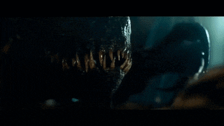 a man stands at a podium in front of a large screen that says indoraptor