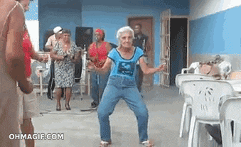 an elderly woman is dancing in front of a group of people in a room .
