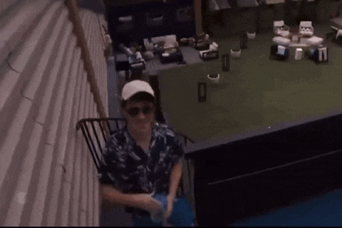 a man wearing sunglasses and a hat is sitting on a staircase in a room .