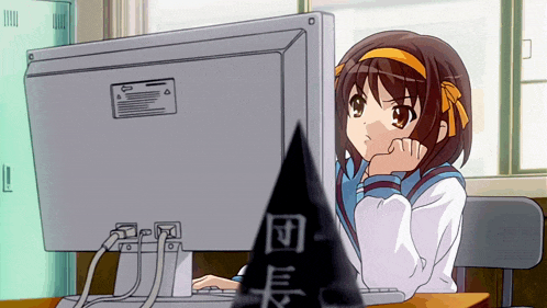 a girl sitting at a desk looking at a computer screen with chinese writing on it