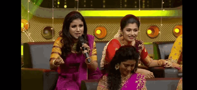 a group of women are sitting in a row on a stage holding microphones .