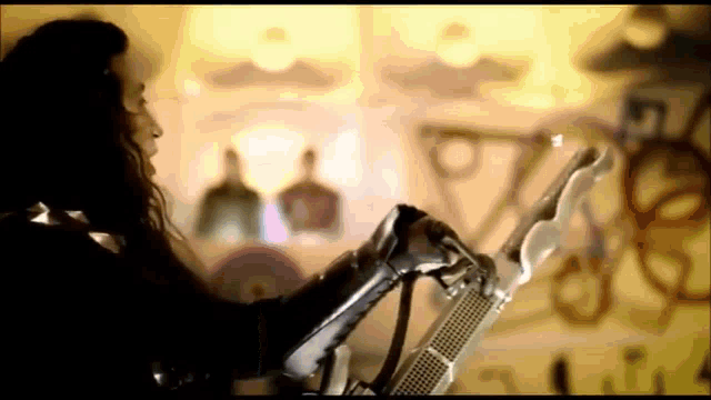 a woman is playing a guitar in front of a wall with graffiti