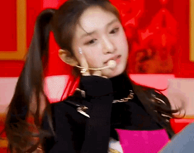 a woman with long hair in a ponytail is wearing a black turtleneck and a pink dress .