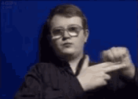 a man wearing glasses is pointing at the camera .