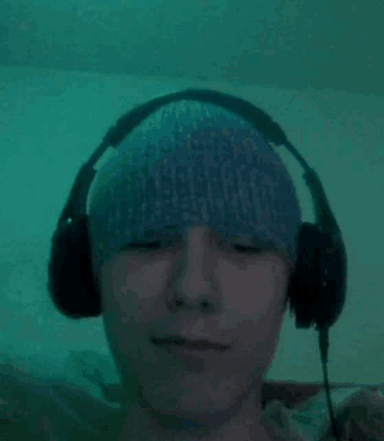 a young man wearing headphones and a beanie