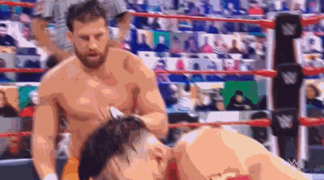 two men are wrestling in a ring with a crowd in the background .