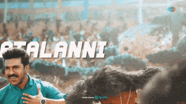 a man in a blue shirt is standing in front of a crowd and the words " atalanni " are visible