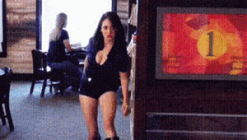 a woman is walking through a restaurant with a sign that says number 1 on it .
