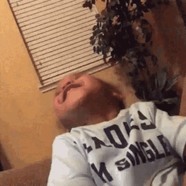 a man is laying on a couch wearing a shirt that says i am single