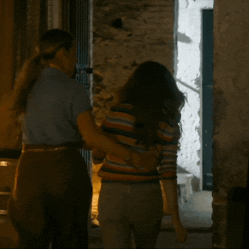a man and a woman are walking down a hallway at night