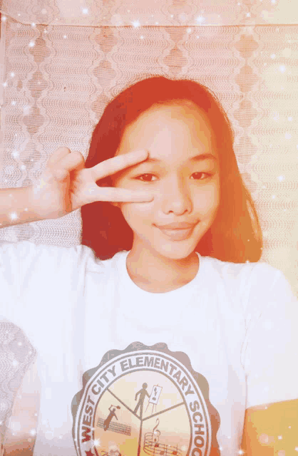 a girl wearing a west city elementary school shirt giving the peace sign