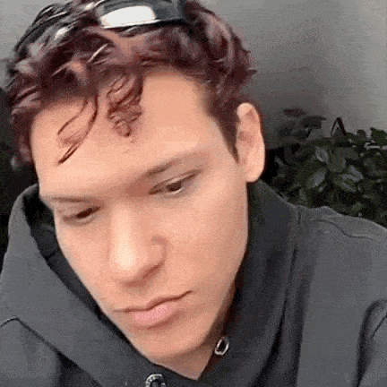 a man wearing sunglasses and a hoodie is looking down .