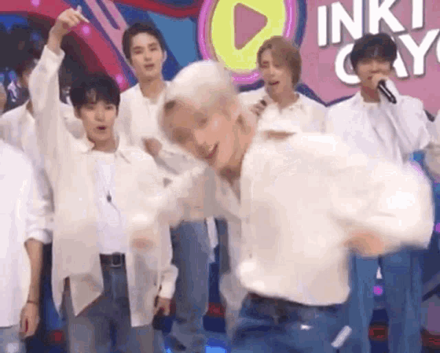 a group of young men are standing on a stage dancing .