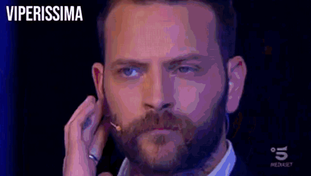 a man with a beard is talking into a microphone with the words viperissima written above him