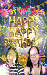 two women are posing for a picture in front of a sign that says happy birthday