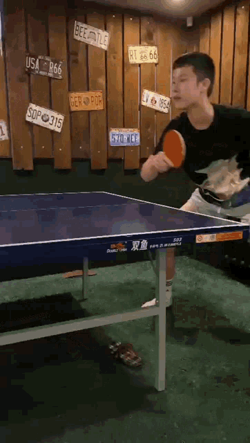 a man is playing ping pong on a table that has a license plate that says rt 66 66