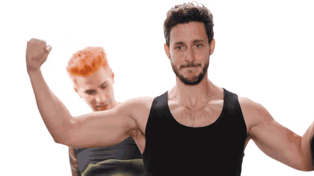 a man with a beard is flexing his muscles in front of another man