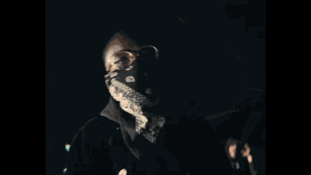 a blurry photo of a man in a hooded jacket holding a gun