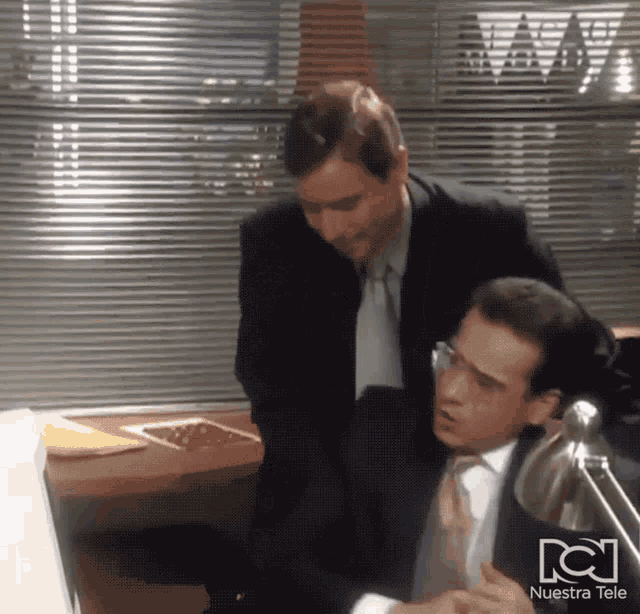 a man in a suit and tie is standing next to another man in a suit and tie in front of a nuestra tele sign