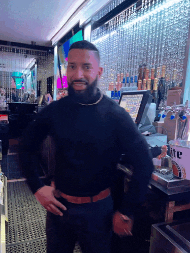 a man in a black turtleneck stands in front of a miller lite bucket