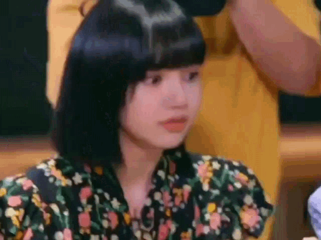 a woman with short black hair is sitting at a table with a man in a yellow shirt .