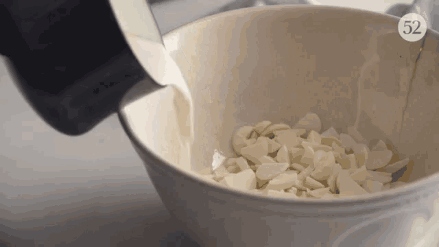 a bowl of chopped almonds is being poured into a bowl with the number 52 on the bottom