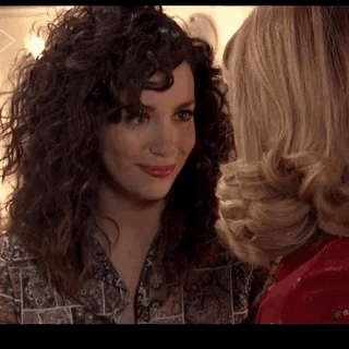 a woman with curly hair looks at another woman