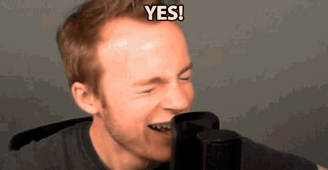 a man says yes in front of a microphone with his eyes closed