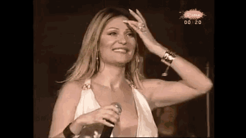 a woman in a white dress is singing into a microphone .
