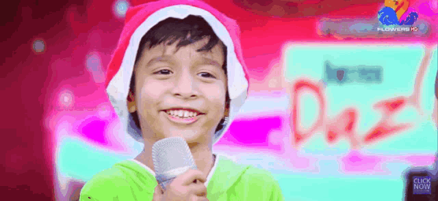a young boy wearing a santa hat holds a microphone and smiles