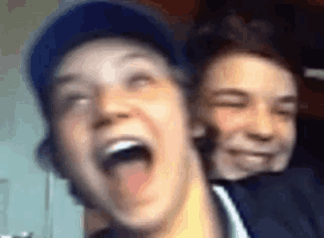 two young men are laughing with their mouths open .