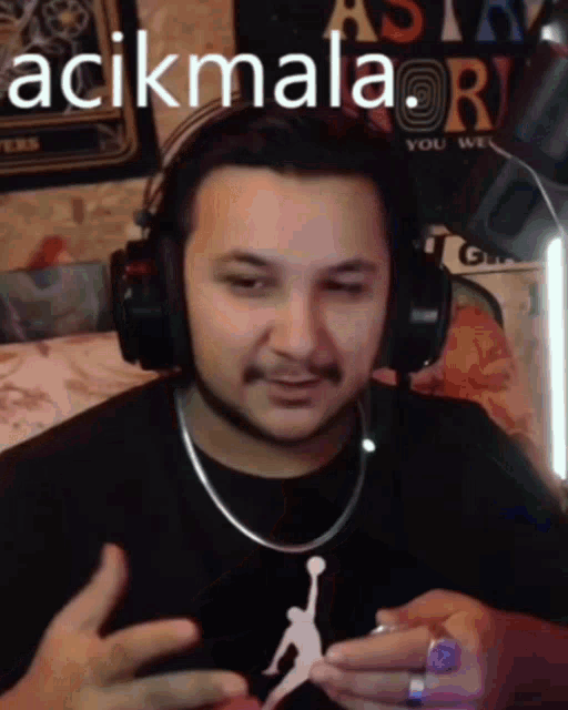 a man wearing headphones and a jordan shirt says açikmala.r