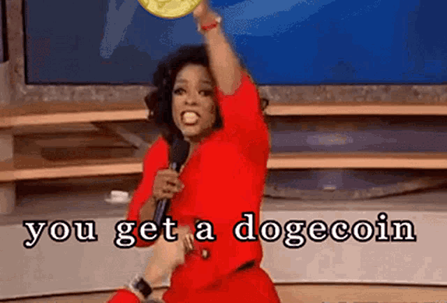 oprah winfrey is holding a dogecoin in her hand while talking into a microphone on a stage .