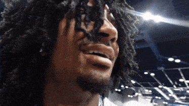 a man with dreadlocks and a beard is smiling with his mouth open