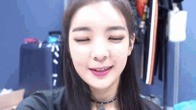 a close up of a woman 's face with her eyes closed and a choker around her neck