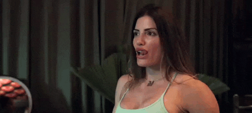 a woman is laughing and clapping her hands at a party while wearing a bikini top .